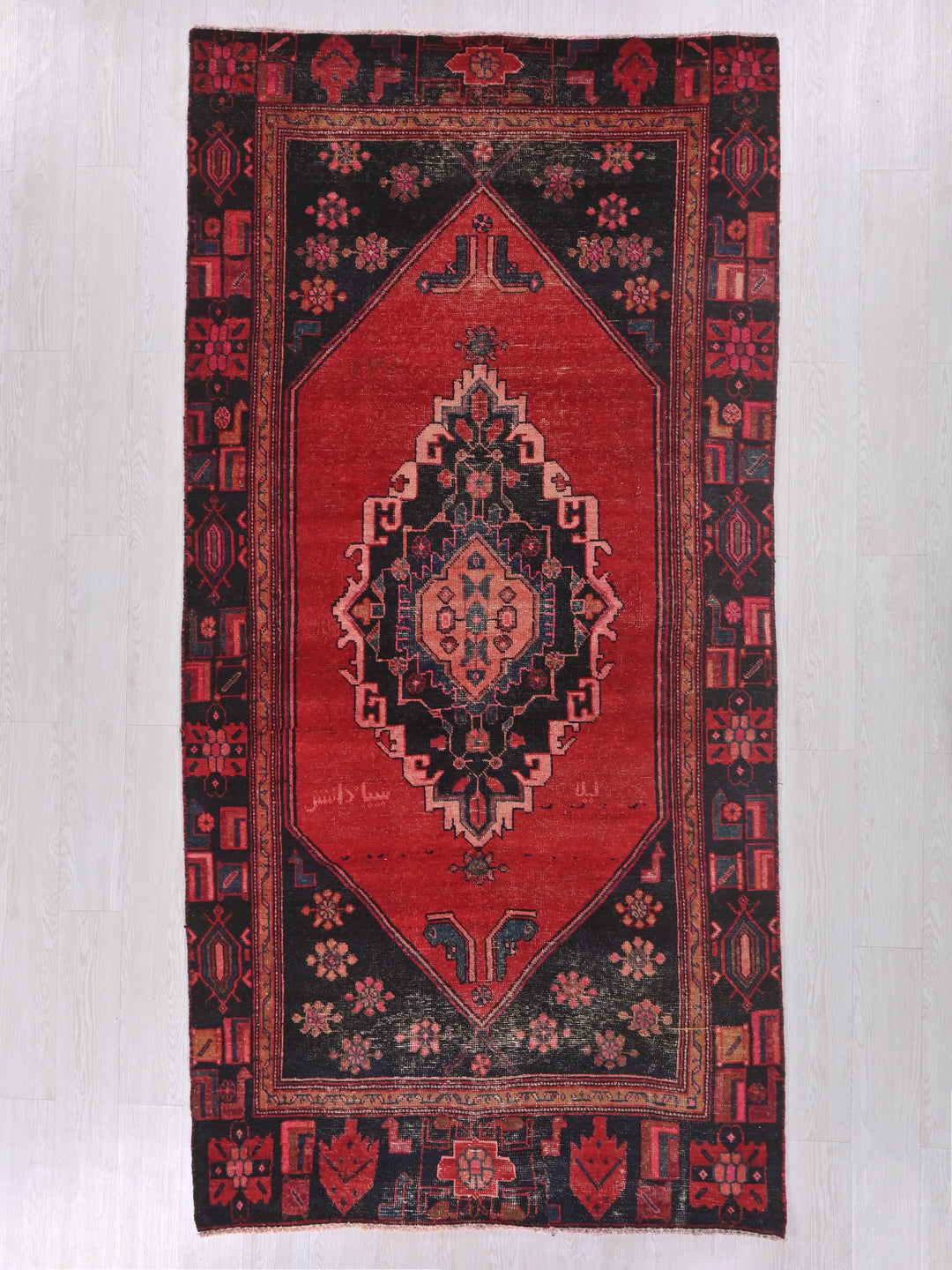 a red and black oriental rug hanging on a wall