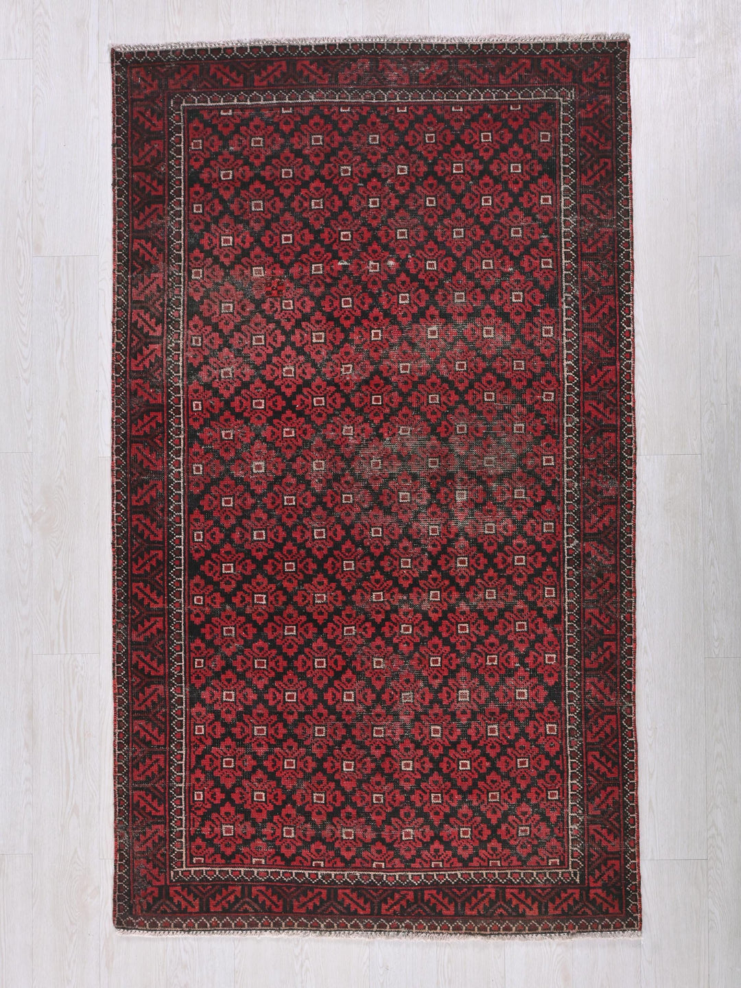 a red and black rug on a white floor