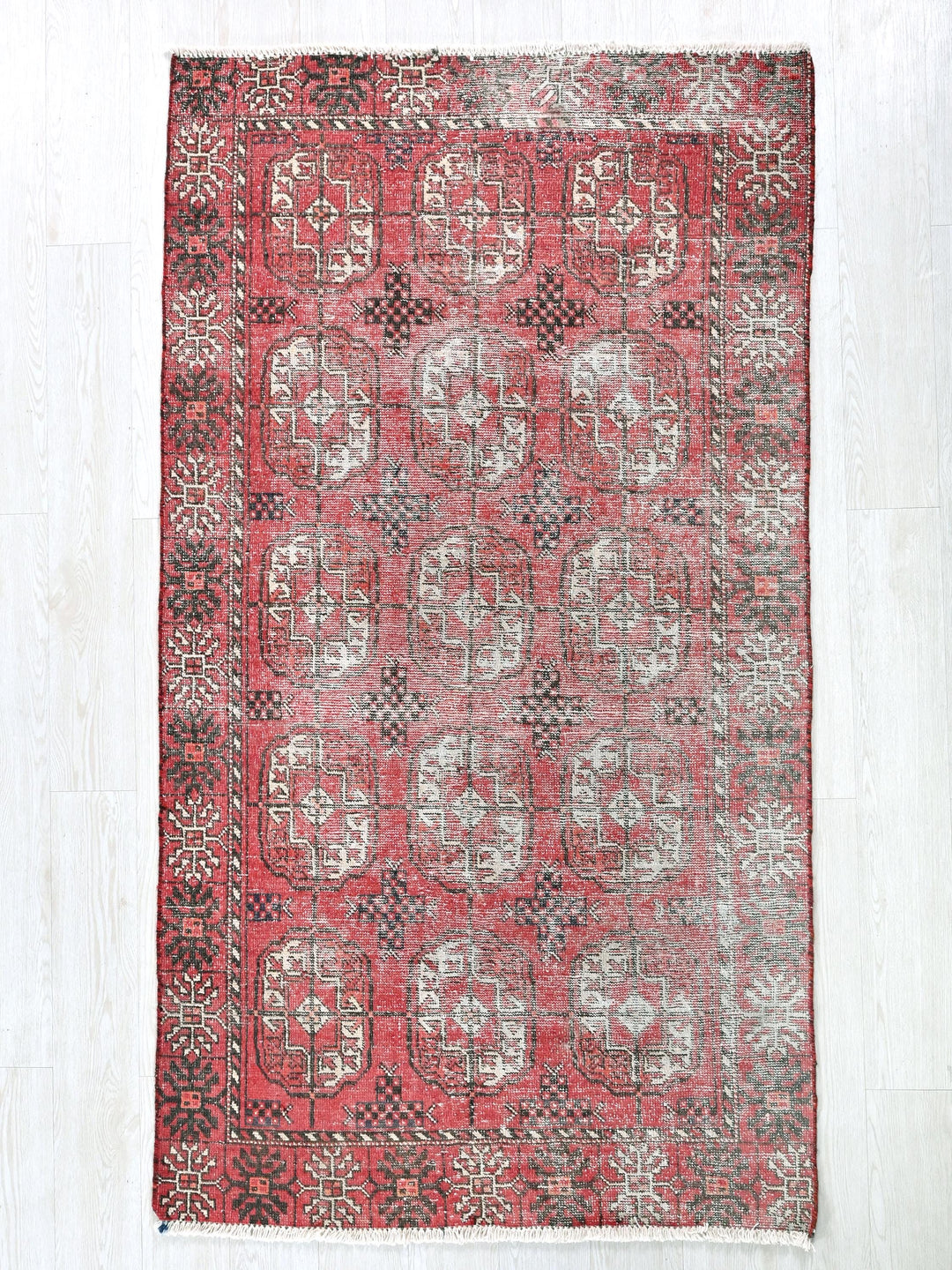 a red and black rug on a white floor