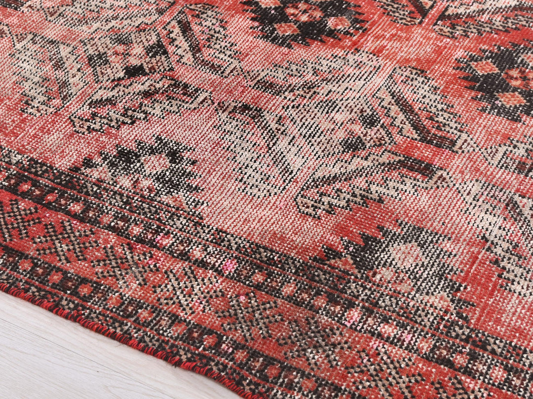 a close up of a red rug on a wooden floor