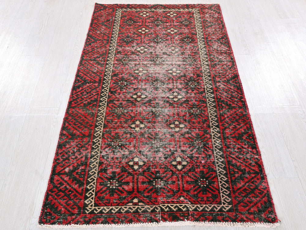 a red and black rug on a white floor