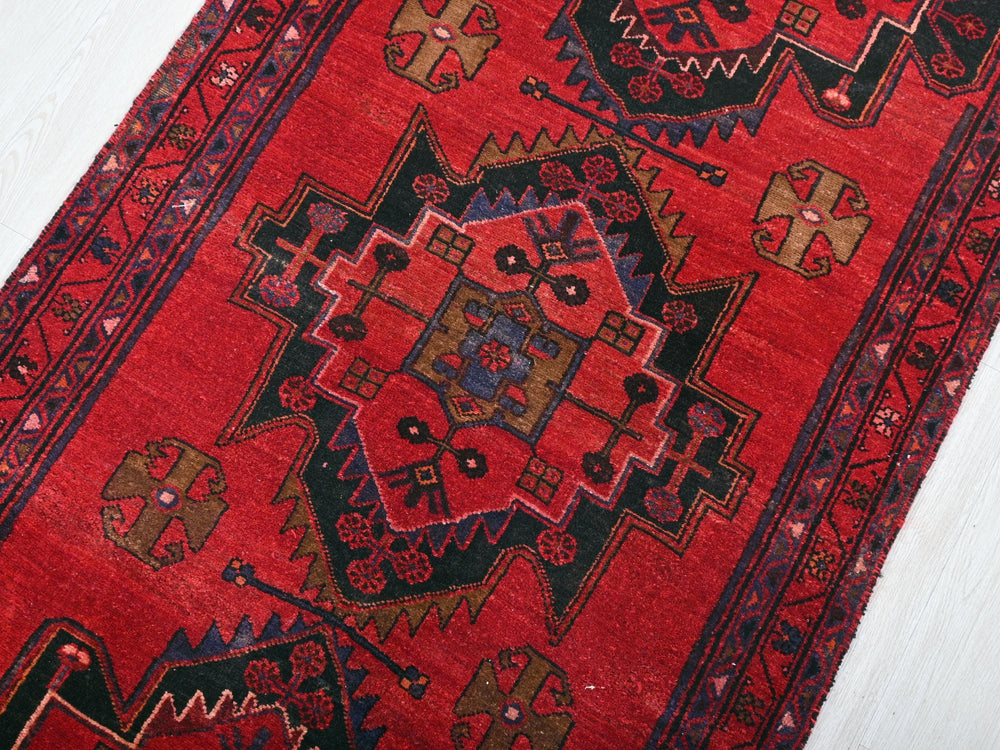 a red rug with a design on the middle of it