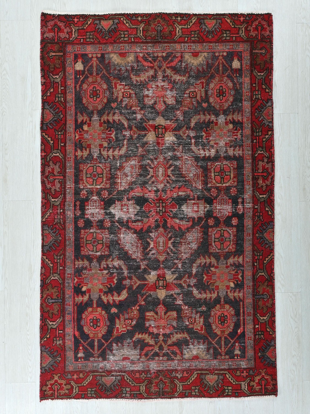 a red and black rug on a white floor