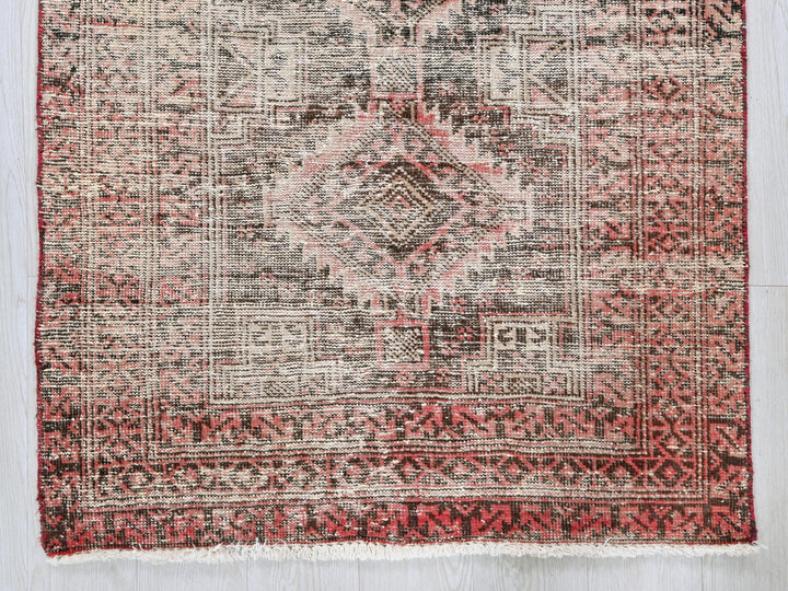 a red and black rug on a wooden floor