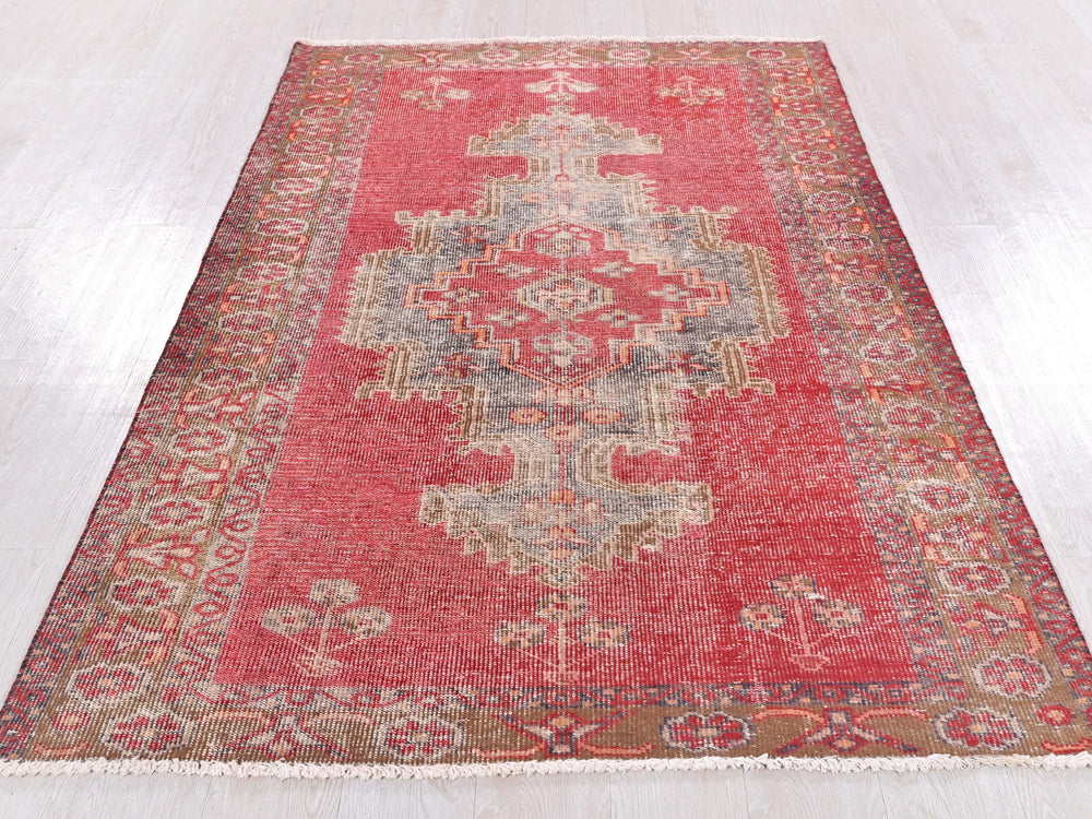 a red rug with a floral design on a wooden floor