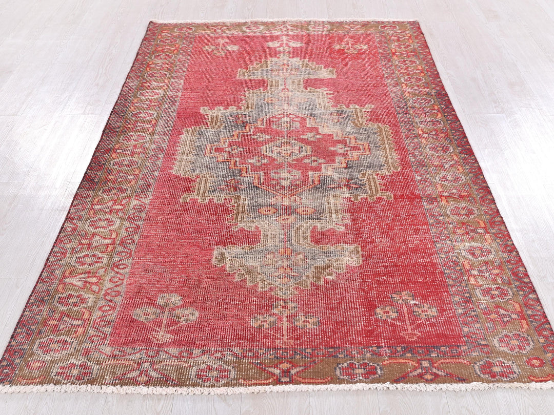 a red rug with a floral design on a wooden floor