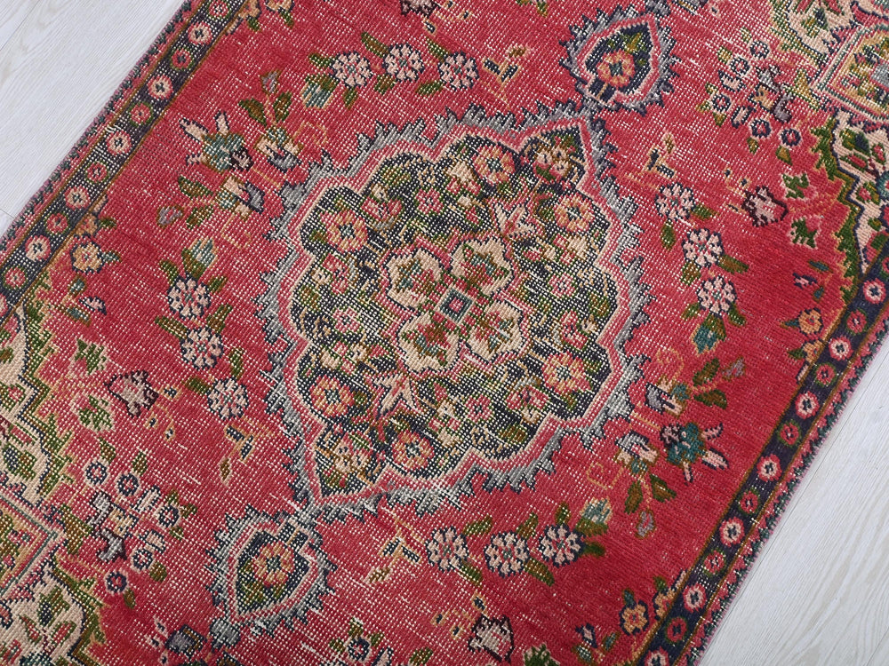 a red rug on a white wooden floor