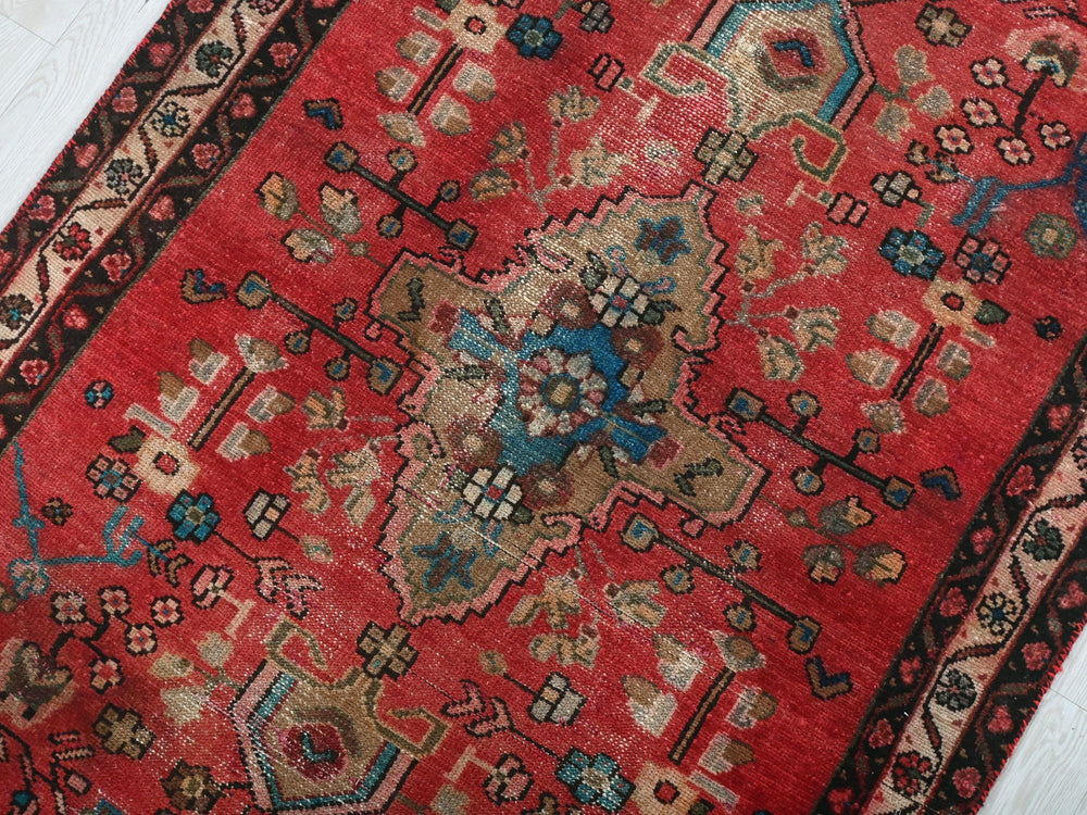a red oriental rug on a white wooden floor