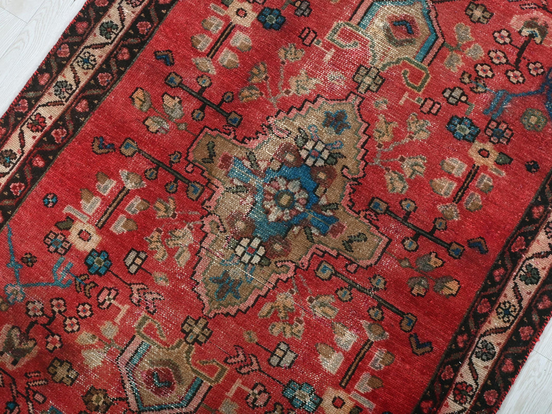 a red oriental rug on a white wooden floor