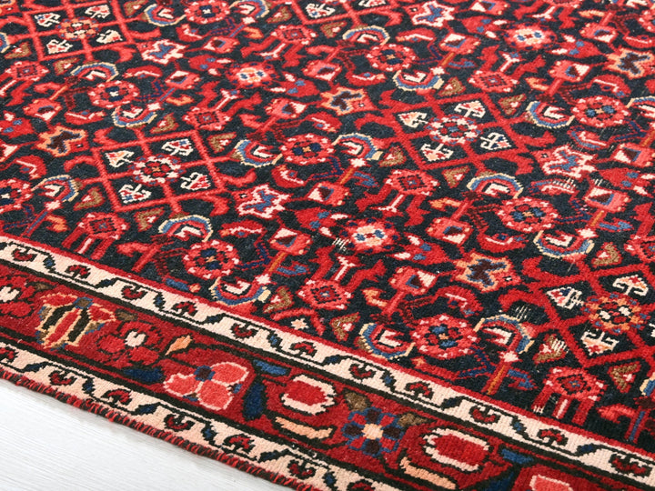 a red and black oriental rug on a white floor