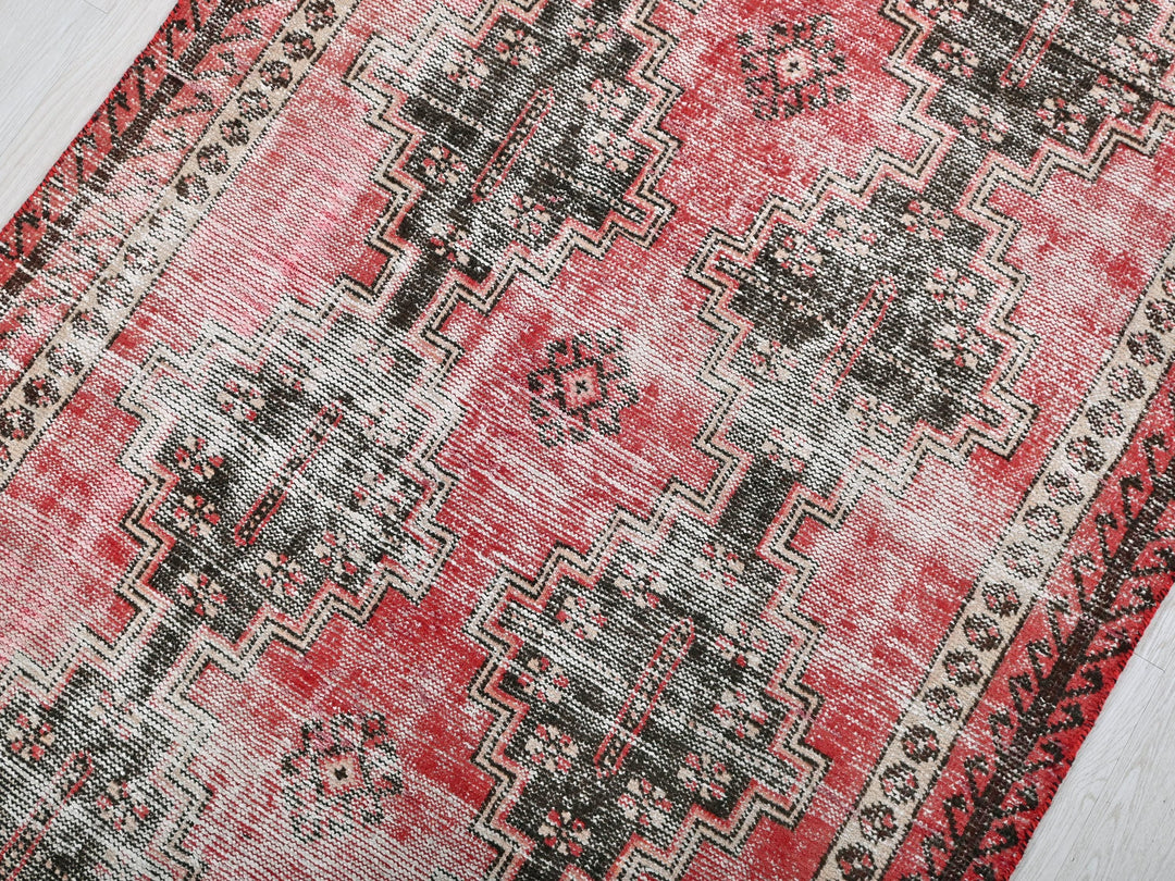 a red and black rug on a wooden floor