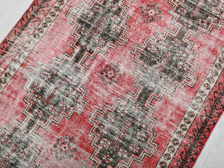 a red and black rug on a wooden floor