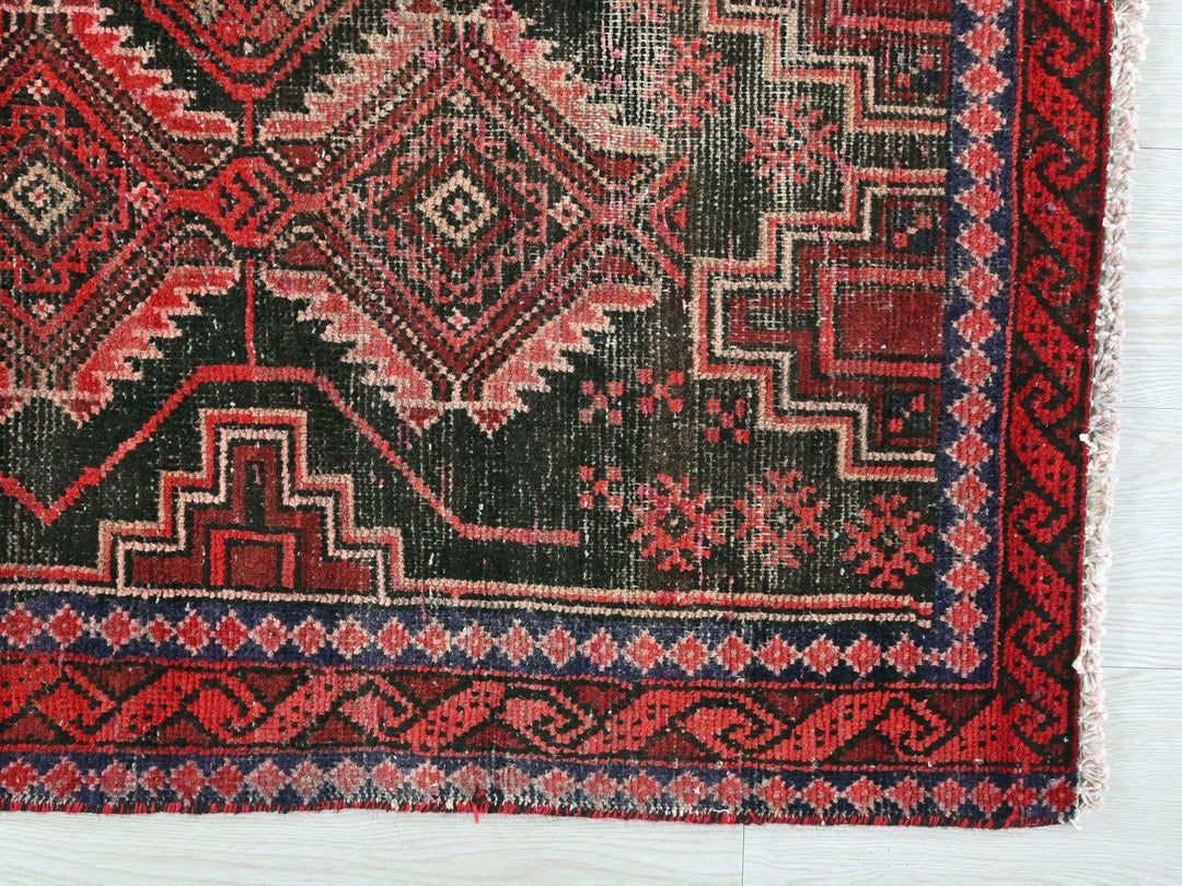 a red and black rug on a white surface