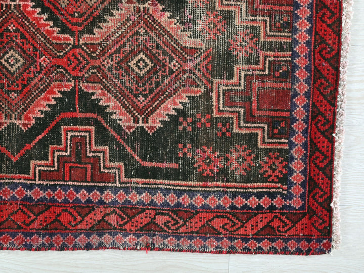 a red and black rug on a white surface