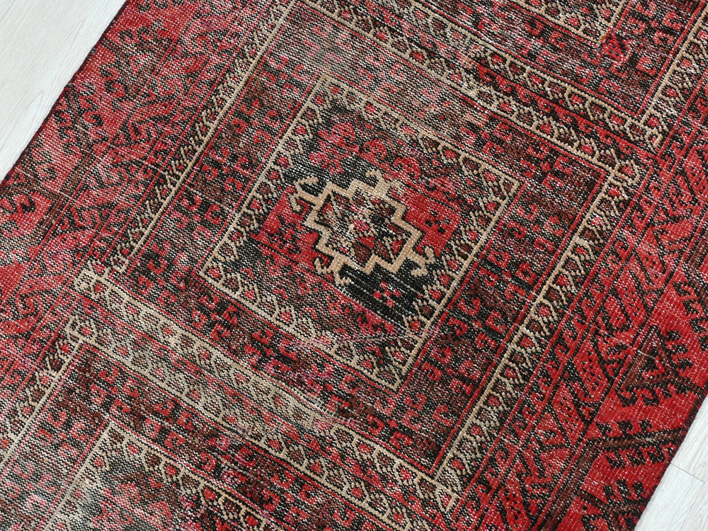 a red and black oriental rug on a wooden floor