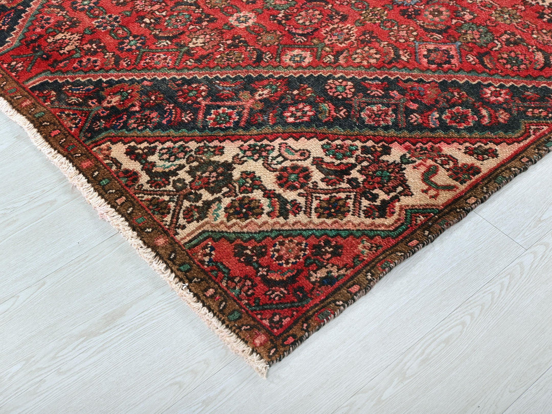 a red oriental rug on a white wooden floor