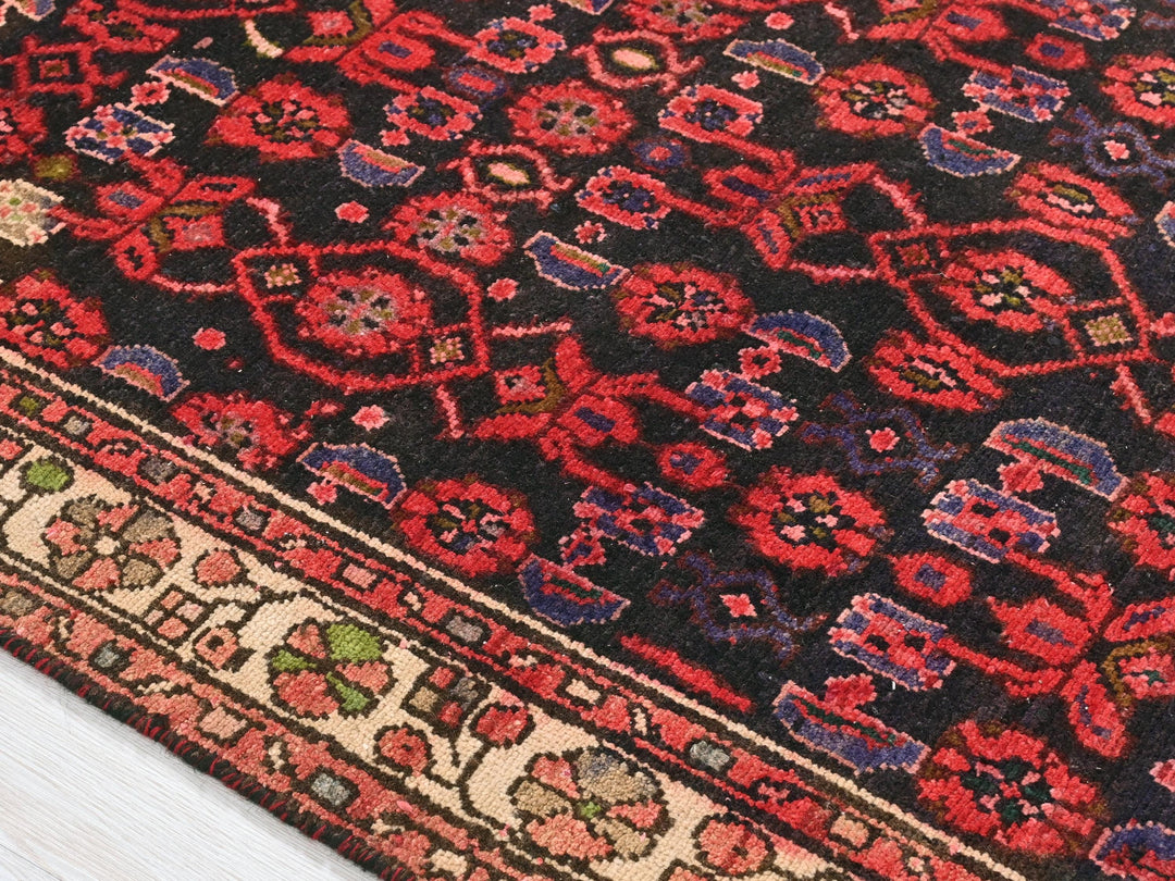 a red and black oriental rug on a wooden floor