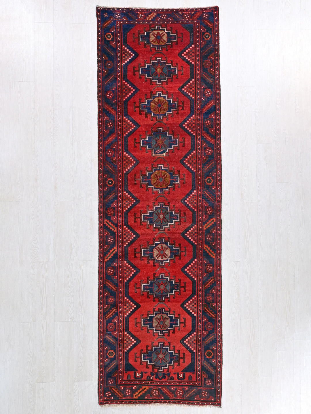 a red and blue rug hanging on a wall