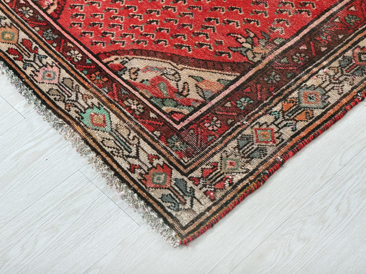 a red oriental rug on a white wooden floor
