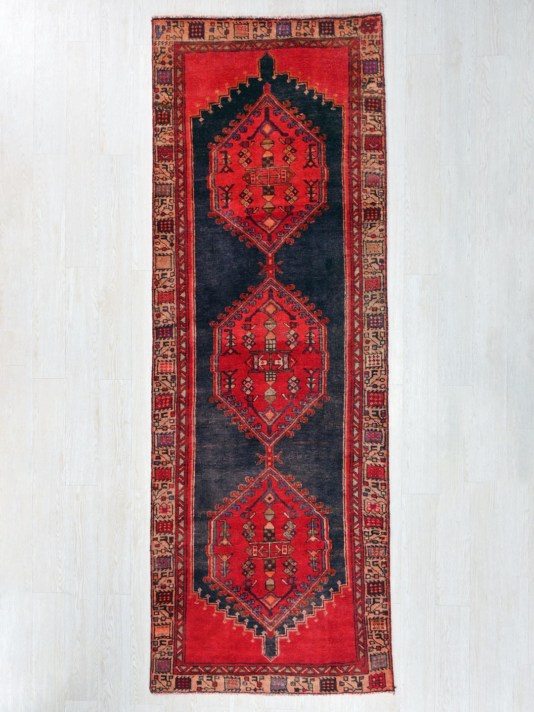a red and black rug hanging on a wall