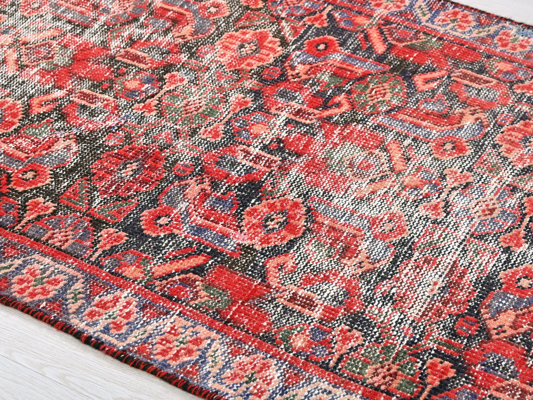 a red and blue rug on a wooden floor