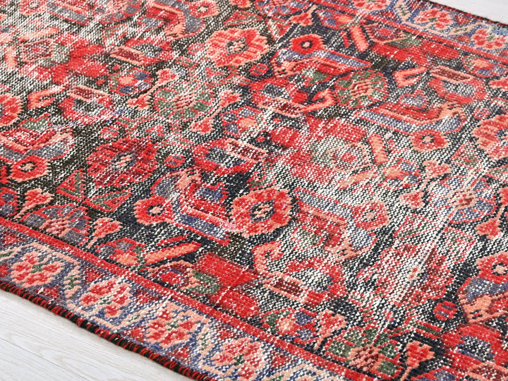 a red and blue rug on a wooden floor