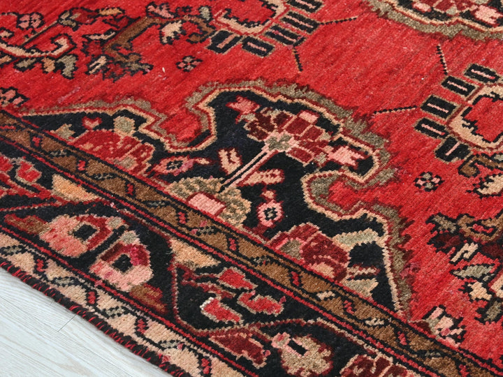 a close up of a red rug on a wooden floor