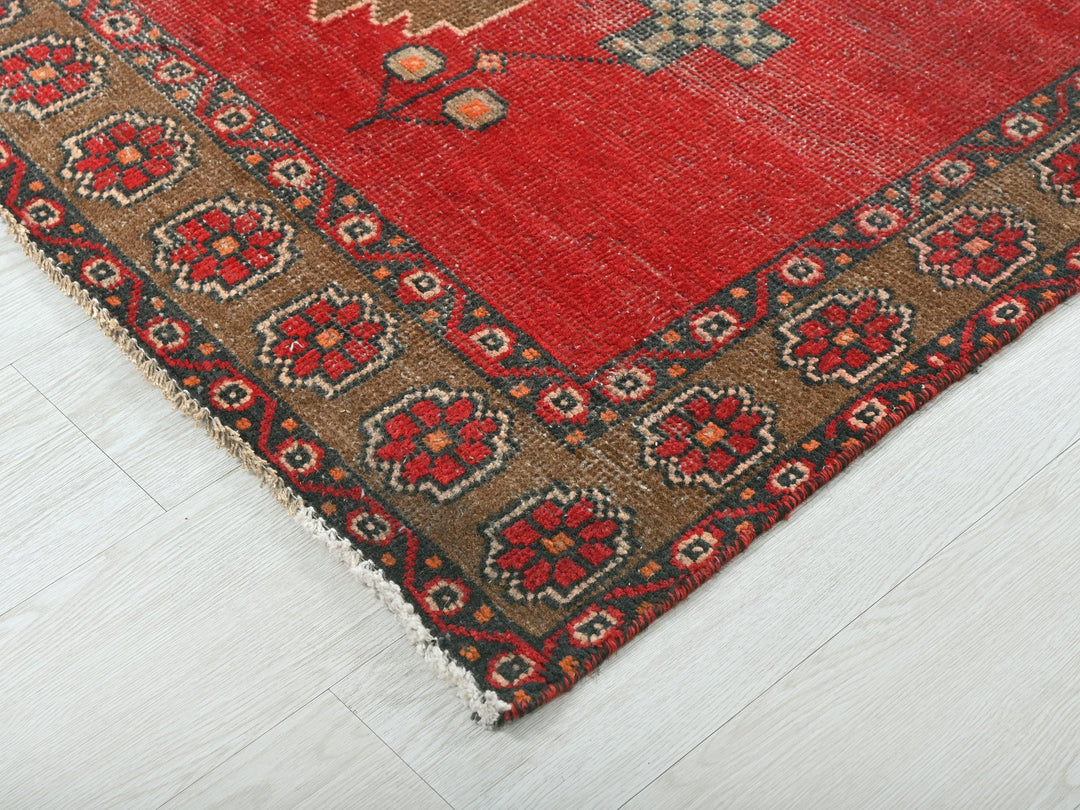 a red rug with a brown border on a white floor