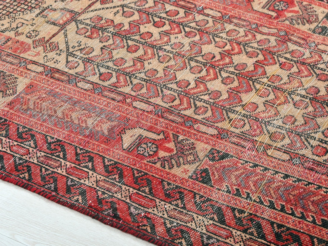 a red and black oriental rug on a wooden floor