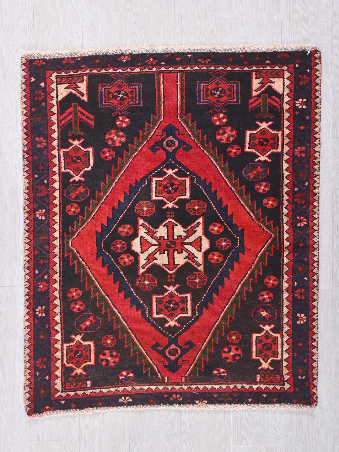 a red and black rug on a white floor