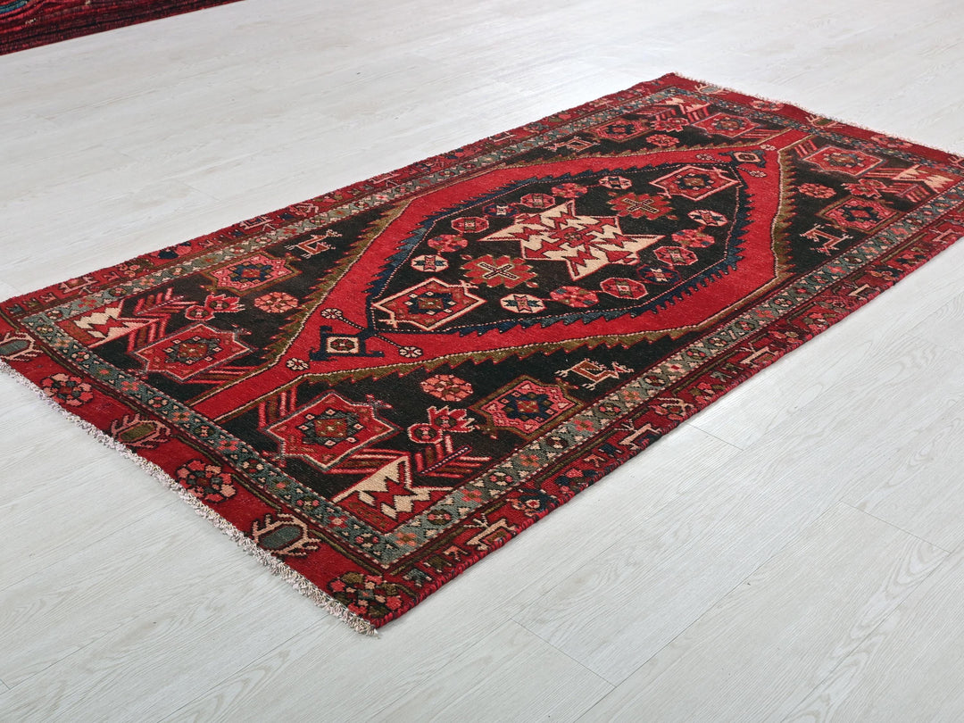 a red and black rug on a white floor