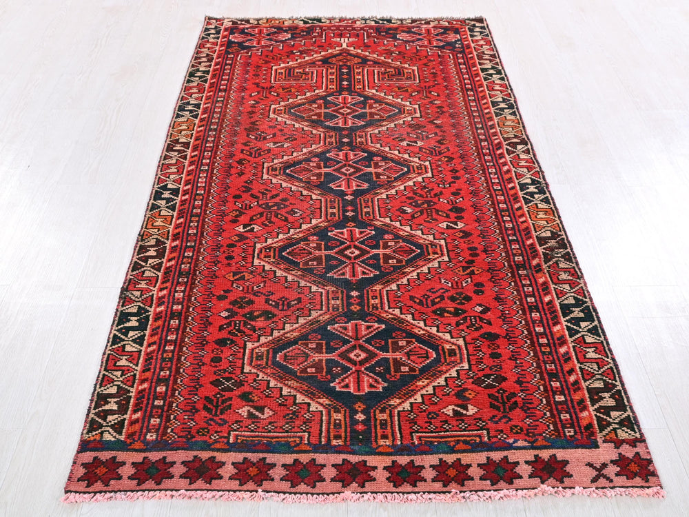 a red rug with a black border on a white floor