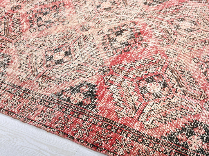 a red and black rug on a wooden floor
