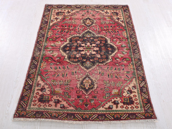 a red rug with a floral design on a white floor