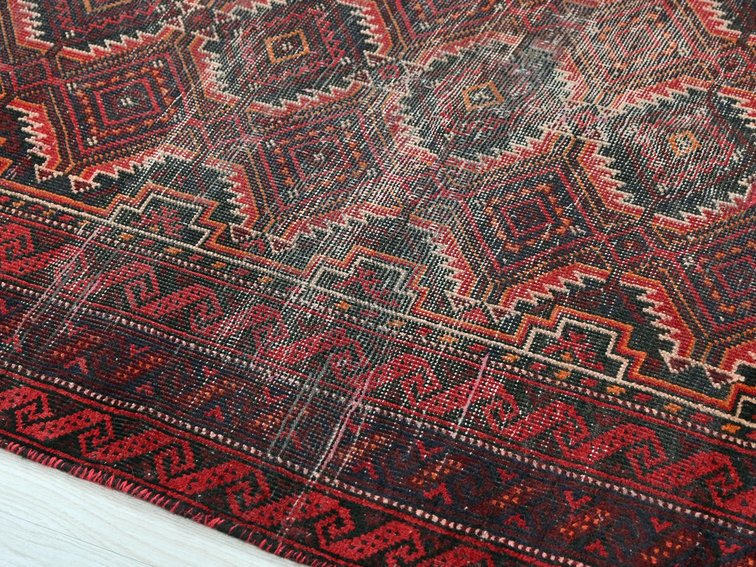 a red and black oriental rug on a wooden floor