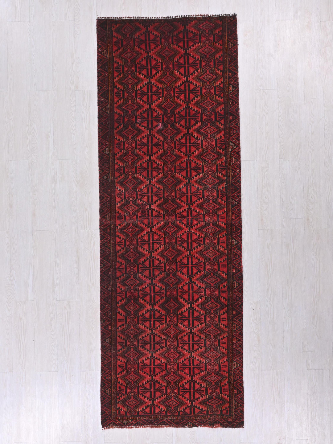 a red and black rug on a white floor