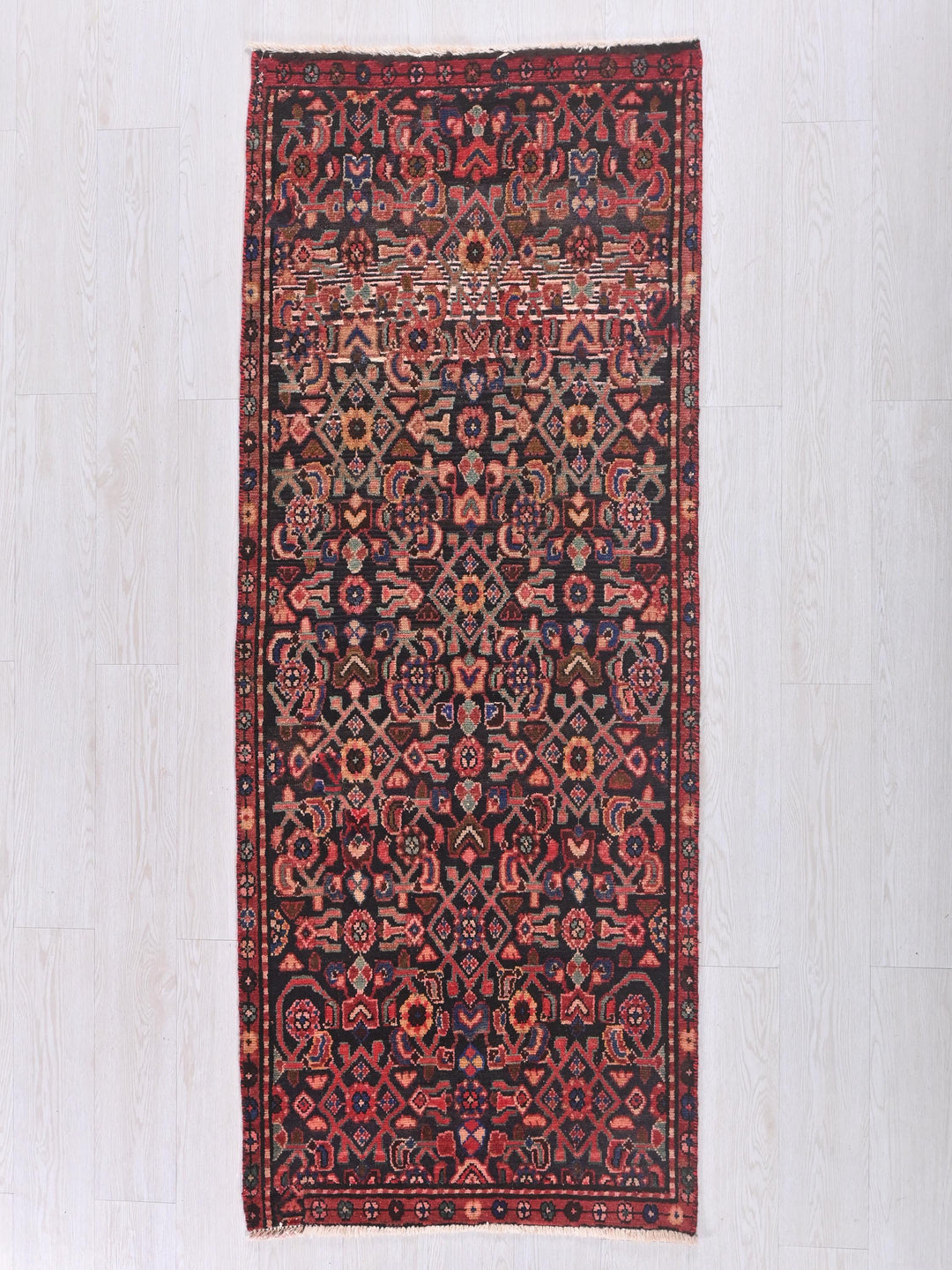 a red and black rug on a white floor