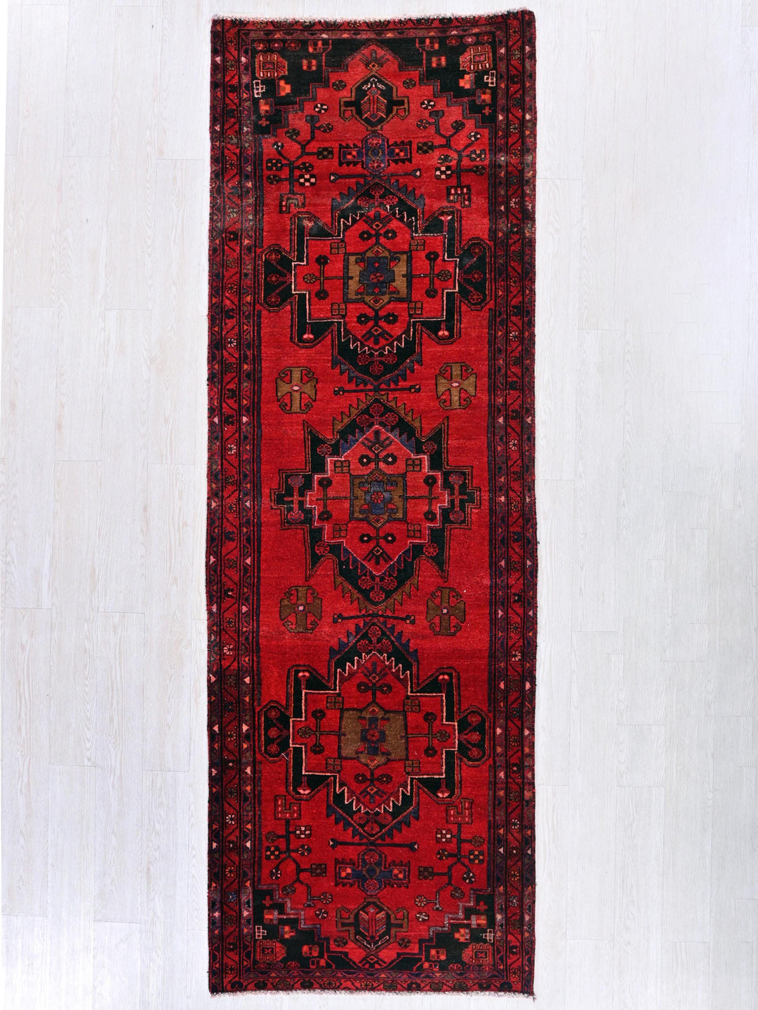 a red rug hanging on a white wall