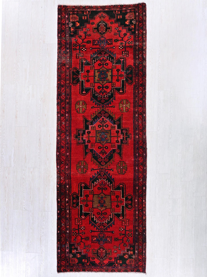 a red rug hanging on a white wall