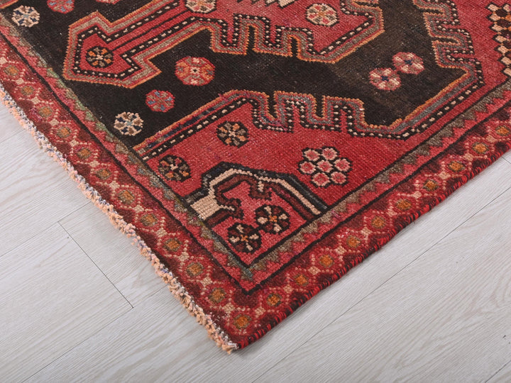a red and black oriental rug on a white floor