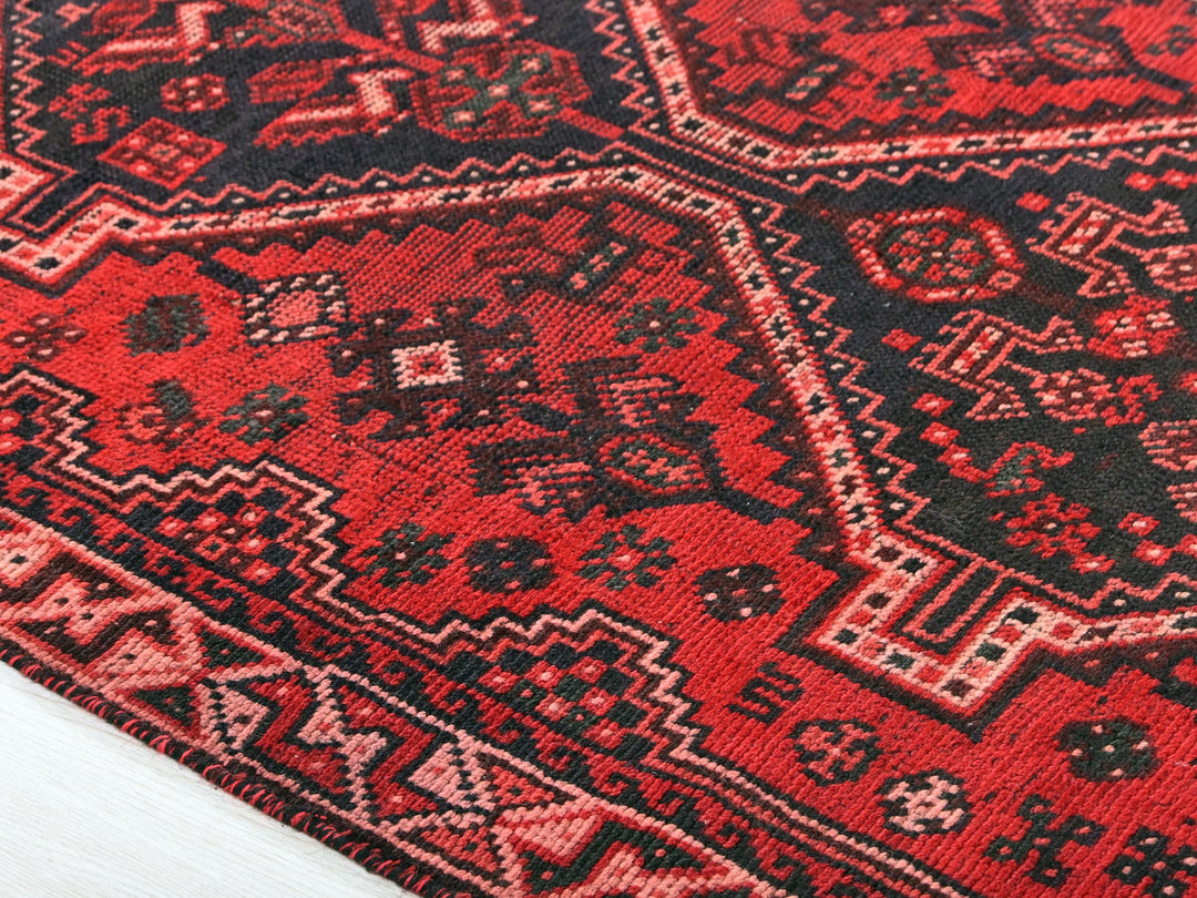 a red and black oriental rug on a white floor