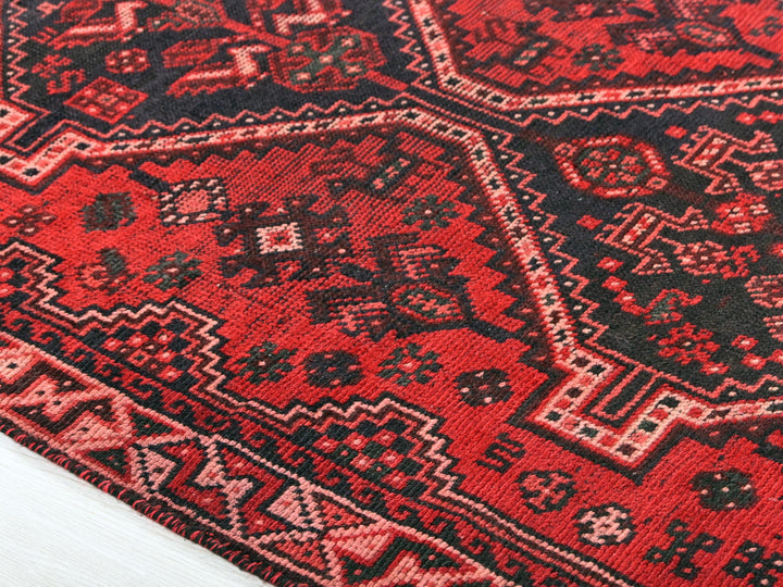 a red and black oriental rug on a white floor