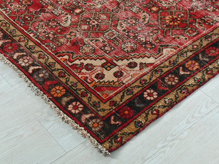 a red oriental rug on a white wooden floor