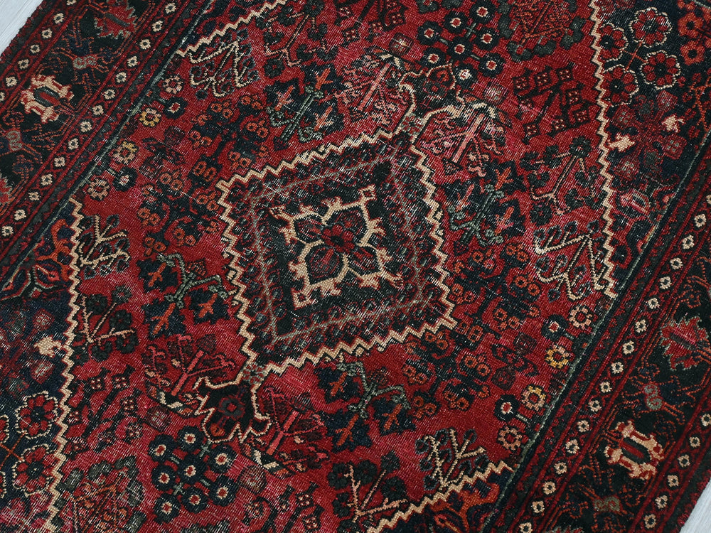 a red and black oriental rug on a white floor