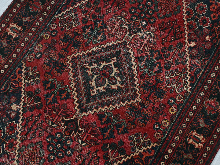 a red and black oriental rug on a white floor
