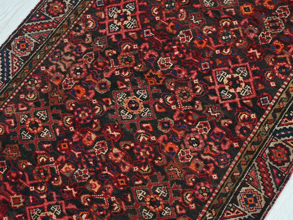 a red and black oriental rug on a white floor