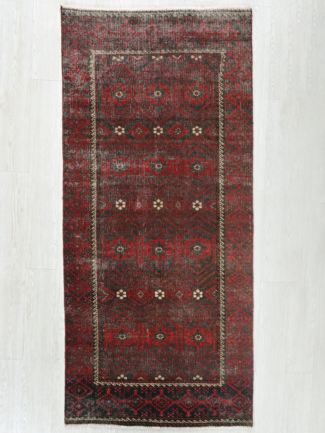 a red rug with a black border on a white floor
