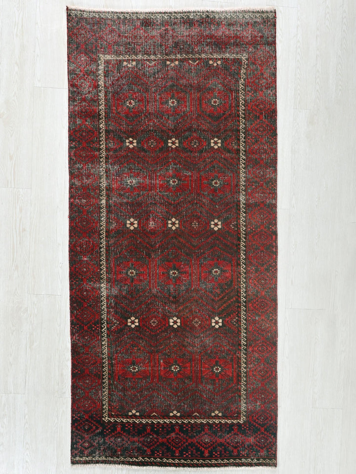 a red rug with a black border on a white floor