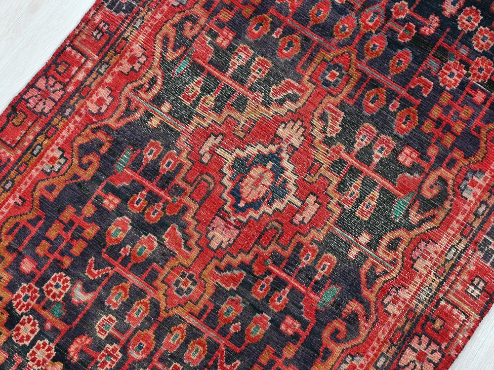 a red and blue oriental rug on a wooden floor