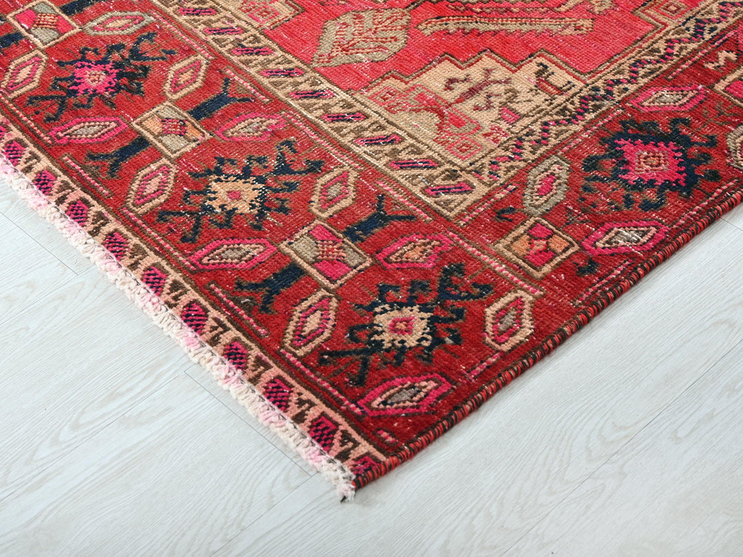 a red oriental rug on a white wooden floor